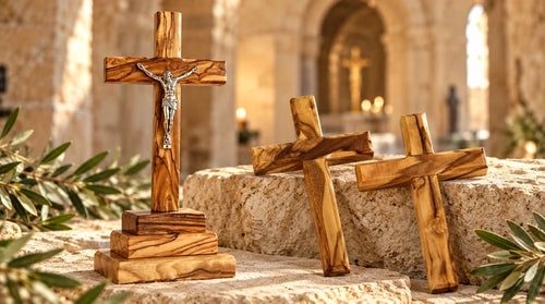 Three olive wood crosses, including a standing crucifix, displayed against a warm stone church backdrop.