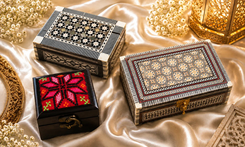 Handcrafted Bethlehem jewelry boxes with mother of pearl inlay and embroidered keepsake box displayed on elegant satin fabric.