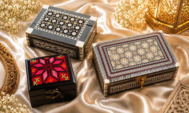 Handcrafted Bethlehem jewelry boxes with mother of pearl inlay and embroidered keepsake box displayed on elegant satin fabric.