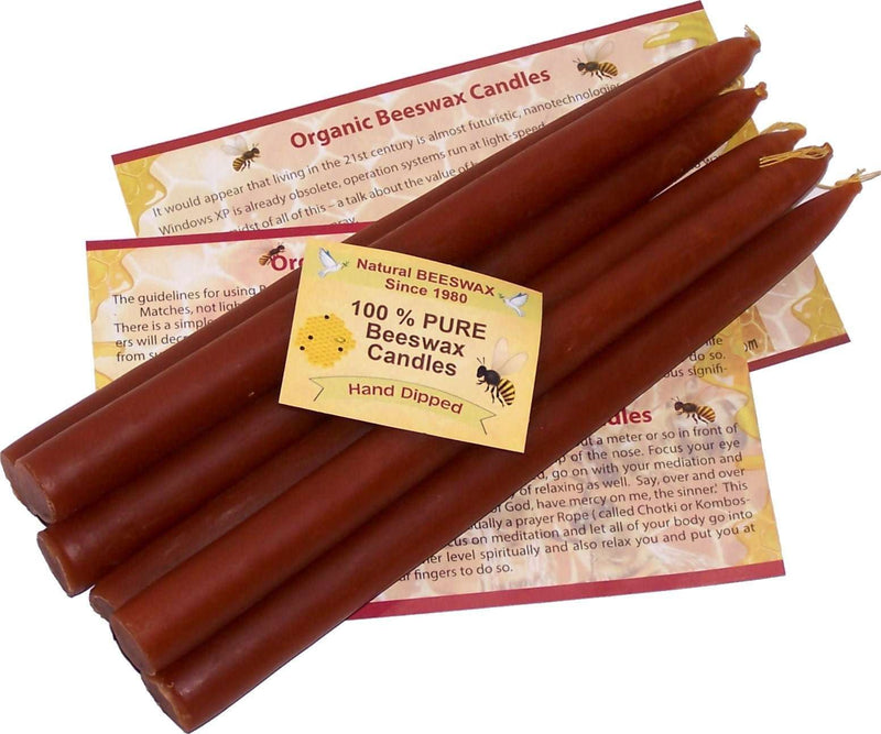 Six brown hand-dipped beeswax taper candles fanned over printed beeswax leaflets